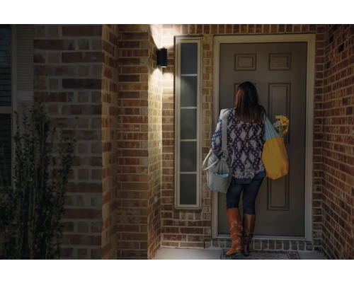 Frau steht vor Haustür mit Aussenleuchte