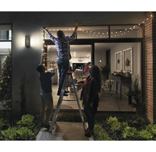 Une famille décore une maison avec une guirlande lumineuse pour une décoration festive.