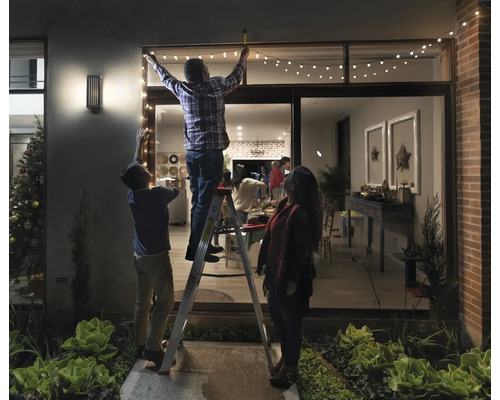 Une famille décore une maison avec une guirlande lumineuse pour une décoration festive.
