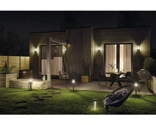 Jardin éclairé avec maison, terrasse, mobilier de jardin et bain à remous la nuit