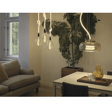 Esszimmer mit Sofa, Esstisch, Zimmerpflanze und verschiedenen Pendelleuchten.