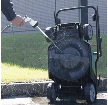 Une tondeuse à gazon est nettoyée avec un tuyau d'arrosage.