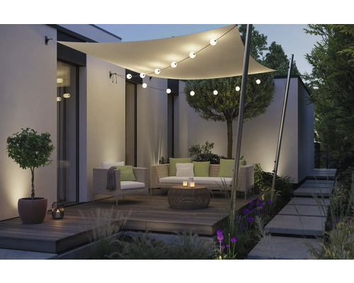 Terrasse aménagée avec voile d'ombrage, guirlande lumineuse et salon de jardin.