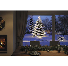 Table à manger décorée pour les fêtes avec vue sur des arbres enneigés et un feu de cheminée