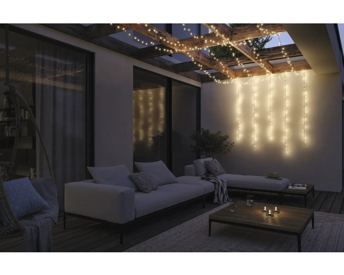 Terrasse éclairée avec guirlandes lumineuses et mobilier de salon