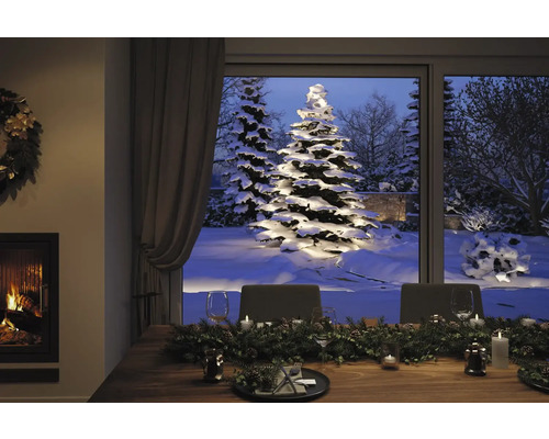 Table dressée de manière festive dans une pièce avec cheminée et vue sur un jardin enneigé