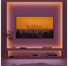 Wohnzimmer mit Fernseher, Regalen und stimmungsvoller Beleuchtung.