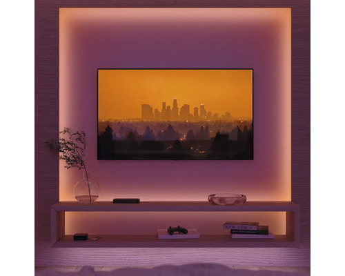 Wohnzimmer mit Fernseher, Regalen und stimmungsvoller Beleuchtung.