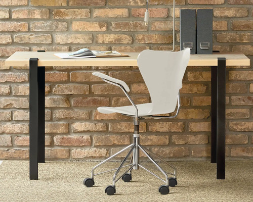 Arbeitszimmer mit Schreibtisch, Bürostuhl und Ordnern vor einer Ziegelwand