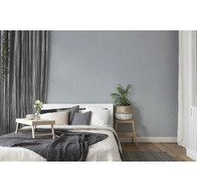 Chambre lumineuse avec lit, oreillers, couverture, table d'appoint et plante d'intérieur