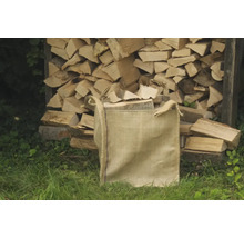 Sac de bois de chauffage devant une pile de bois