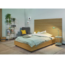 Chambre avec lit, table de chevet, lampe, fauteuil et bibliothèque