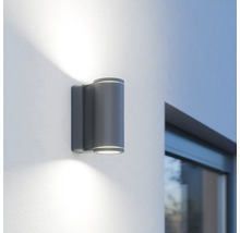 Graue LED-Aussenwandleuchte mit zylindrischem Design an einer Wand