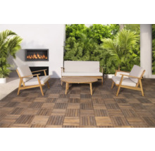 Gartenlounge-Set mit Sofa, Sesseln und Tisch auf Holzfliesen, ergänzt durch einen Wandkamin