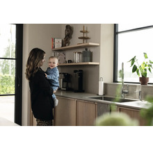 Cuisine claire avec étagères, évier, robinet et mère avec enfant