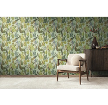 Ein Zimmer mit einer mit Dschungelmotiven tapezierten Wand, einem Sessel und einem Sideboard.