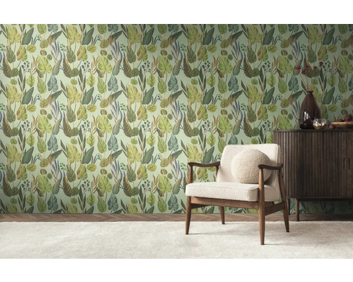Ein Zimmer mit einer mit Dschungelmotiven tapezierten Wand, einem Sessel und einem Sideboard.