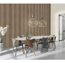 Salle à manger avec table à manger, chaises et suspensions devant un mur avec papier peint imitation bois