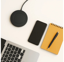 Drahtlose Ladestation, Laptop, Smartphone, Notizblock und Stift auf einem Tisch