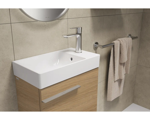 Lavabo avec robinetterie, serviette et miroir dans la salle de bain