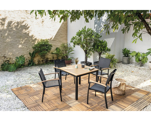 Table de jardin carrée avec quatre chaises sur plancher en bois dans un jardin.