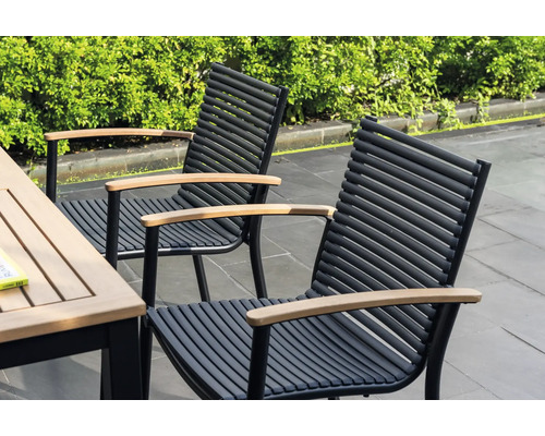 Deux chaises de jardin avec accoudoirs en bois et cadres en métal noir se trouvent à côté d'une table de jardin.