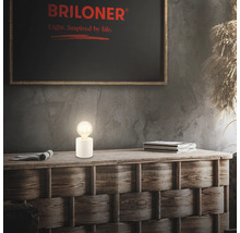 Dekorative Lampe auf Holzkommode mit Briloner Logo im Hintergrund