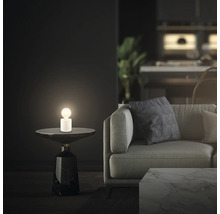 Szene mit Tischleuchte auf Beistelltisch neben einem Sofa in einem Wohnzimmer