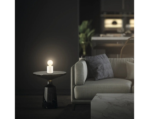 Szene mit Tischleuchte auf Beistelltisch neben einem Sofa in einem Wohnzimmer
