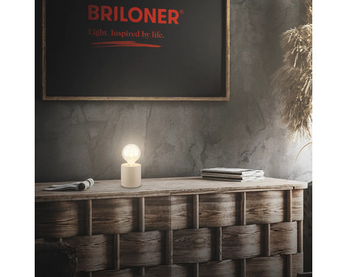 Dekorative Szene mit Briloner Logo, Tischleuchte, Zeitschriften und Kommode