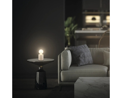 Tischleuchte auf Beistelltisch neben Sofa im Wohnzimmer.