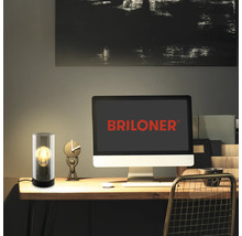 Schreibtischszene mit dekorativer Glas Tischleuchte und einem Computerbildschirm mit Briloner Logo