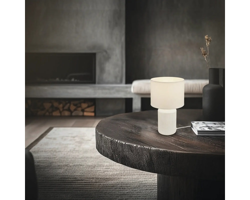 Dekorative Tischleuchte auf einem Tisch in einem Wohnzimmer mit Kamin