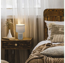 Nachttischlampe auf einem Nachttisch neben einem Bett in einem Schlafzimmer.