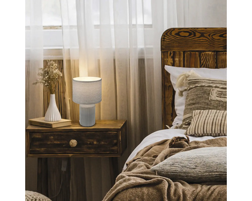 Nachttischlampe auf einem Nachttisch neben einem Bett in einem Schlafzimmer.