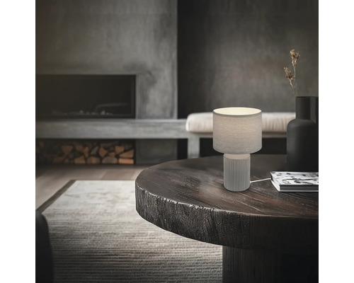 Tischleuchte auf einem runden Tisch in einem Wohnzimmer mit Kamin