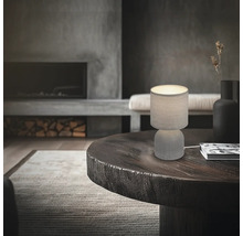 Tischleuchte auf einem runden Holztisch in einem Wohnzimmer