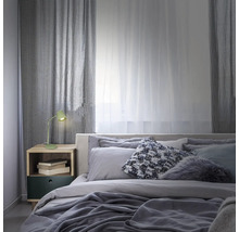 Schlafzimmer mit Bett, Nachttisch, Lampe und Vorhängen