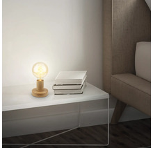 Tischleuchte mit Holzfuss und Glühbirne neben einem Stapel Bücher auf einem Nachttisch