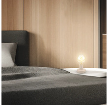 Schlafzimmerszene mit Bett und Nachttischlampe für eine gemütliche Atmosphäre.