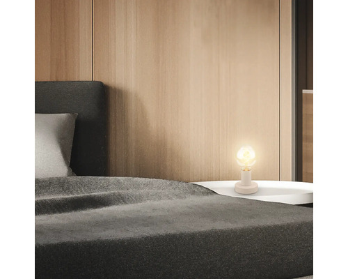 Schlafzimmerszene mit Bett und Nachttischlampe für eine gemütliche Atmosphäre.