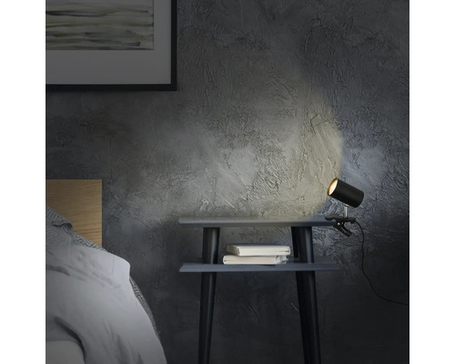 Nachttisch mit Klemmleuchte und zwei Büchern in einem Schlafzimmer