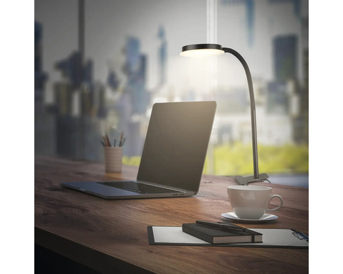 Schreibtisch mit Laptop, Tasse Kaffee, Notizblock und LED-Klemmleuchte