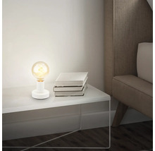 Tischleuchte mit Glühbirne auf Nachttisch neben Buchstapel