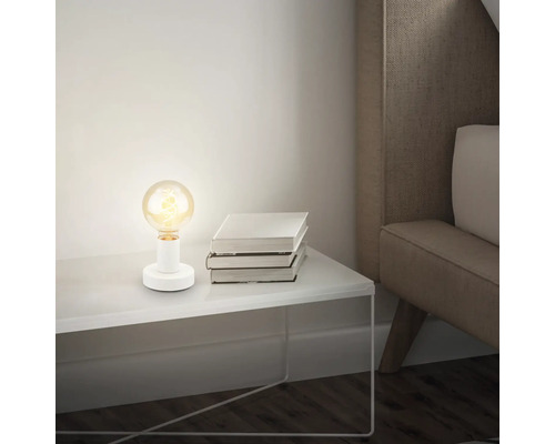 Tischleuchte mit Glühbirne auf Nachttisch neben Buchstapel