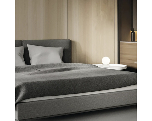 Schlafzimmerszene mit Bett, Nachttisch und Lampe