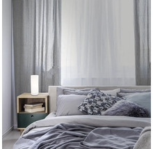 Schlafzimmer mit Bett, Nachttisch und zylindrischer Tischleuchte