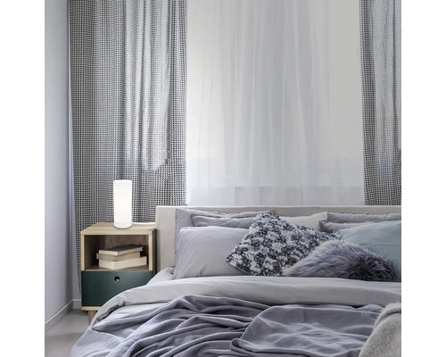 Schlafzimmer mit Bett, Nachttisch und zylindrischer Tischleuchte