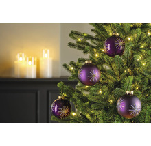 Nahaufnahme eines geschmückten Weihnachtsbaums mit lila Christbaumkugeln und warmweißen Lichtern