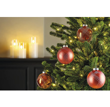 Weihnachtsbaum geschmückt mit roten Kugeln und Lichtern, im Hintergrund Kerzen.